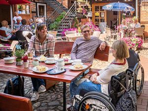 Urlaubsgäste mit Rollstuhl in der Kaffeestube im Hof